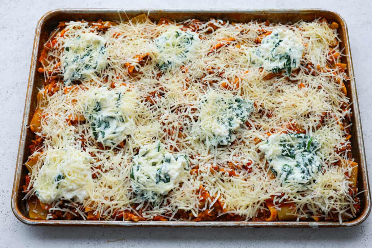 Shredded cheese sprinkled on top of sheet pan lasagna. 