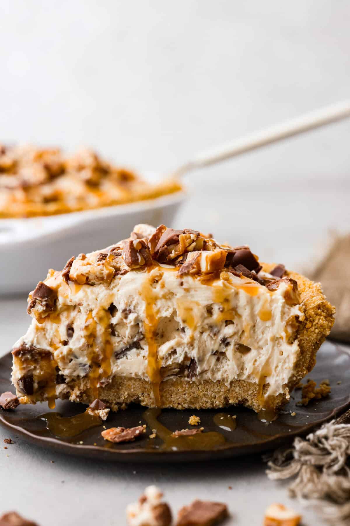 A slice of no bake snicker bar pie on a black plate. 