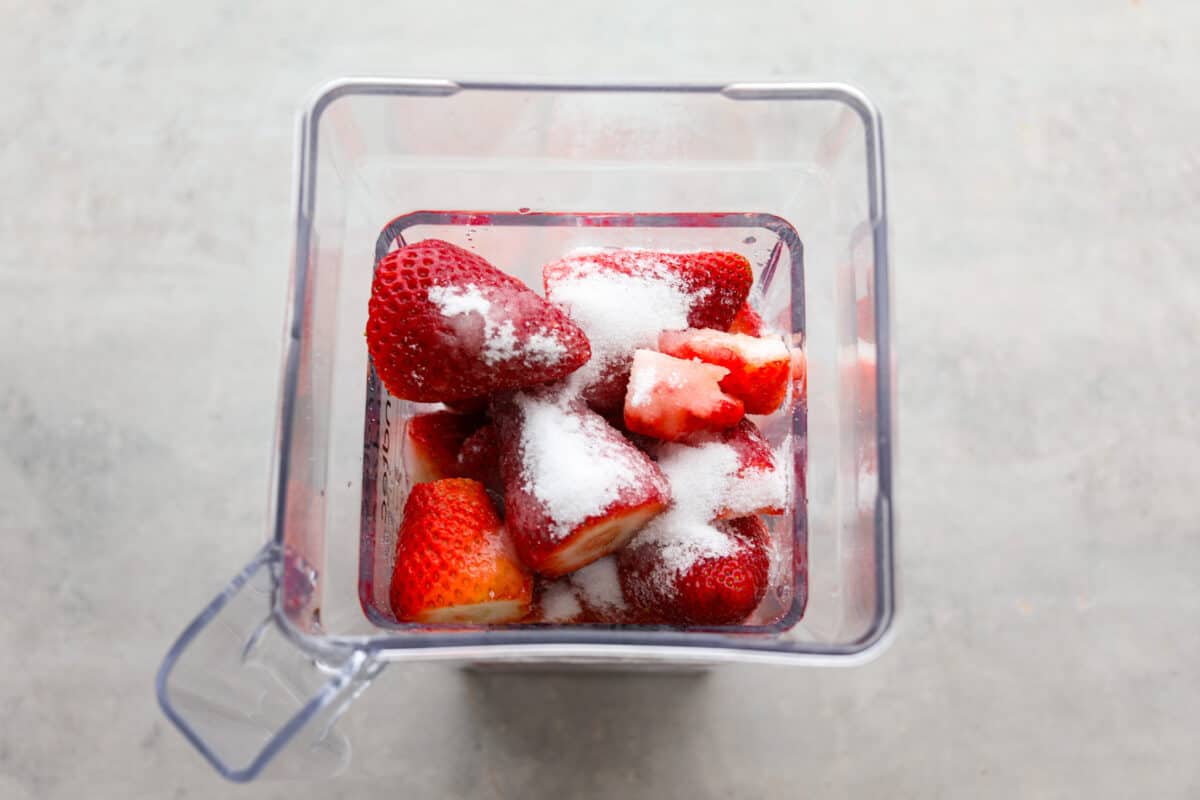 Process photo of the strawberries, sugar, and lemon juice added to a blender.