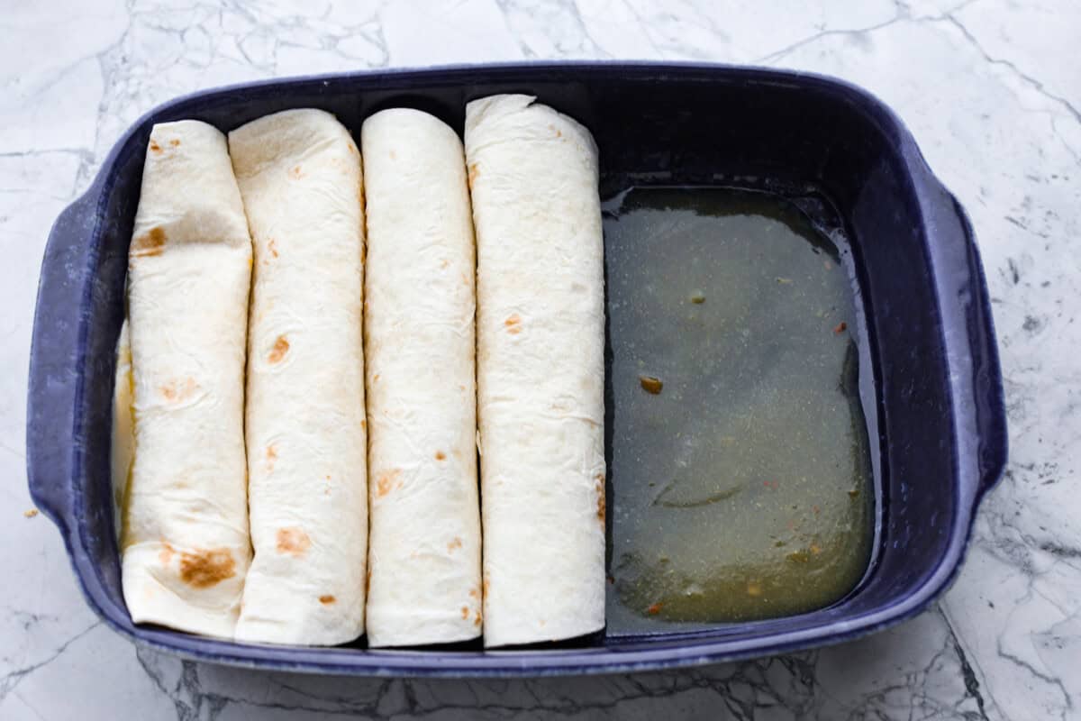 Third photo of the enchiladas rolled and placed into the baking dish.