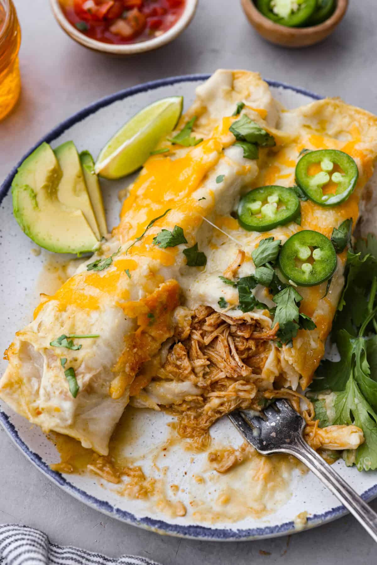 Close view of honey lime chicken enchiladas plated with a fork.