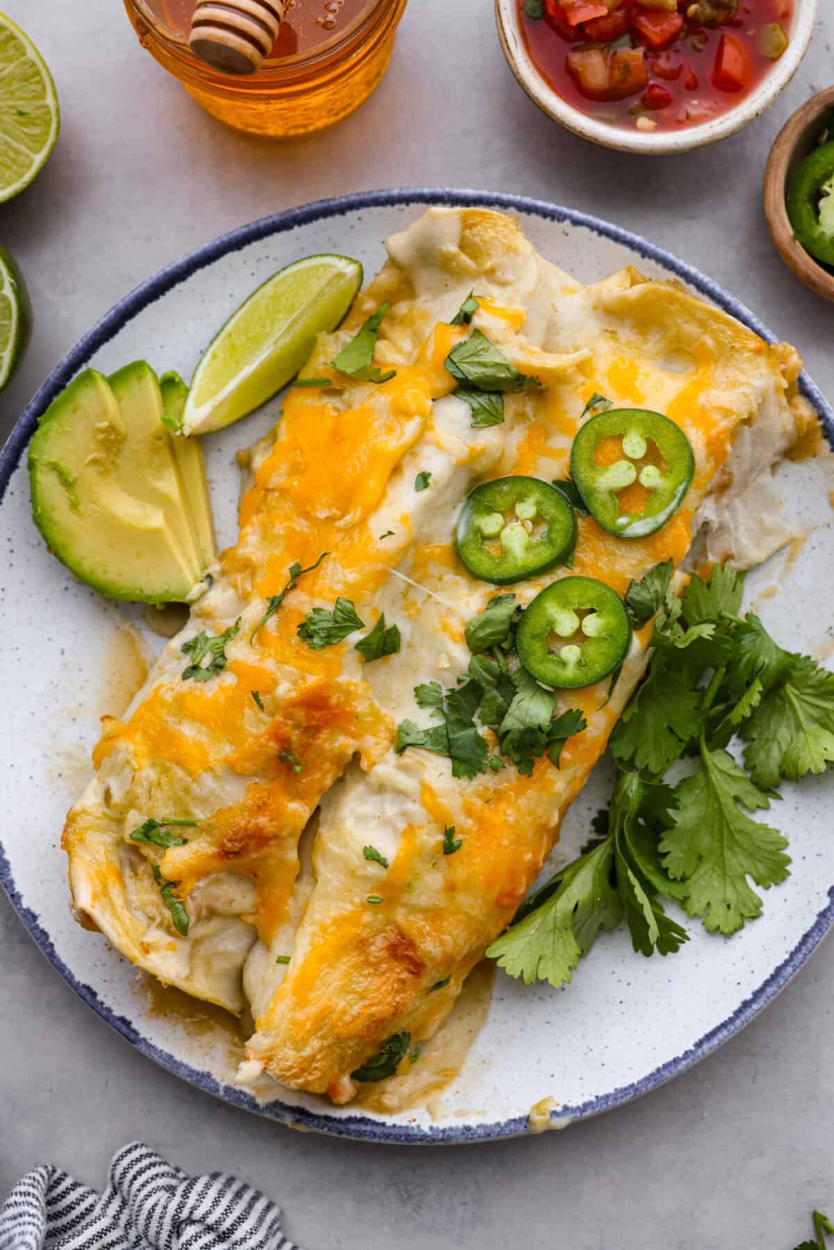 Close top view of honey lime chicken enchiladas plated and garnished.