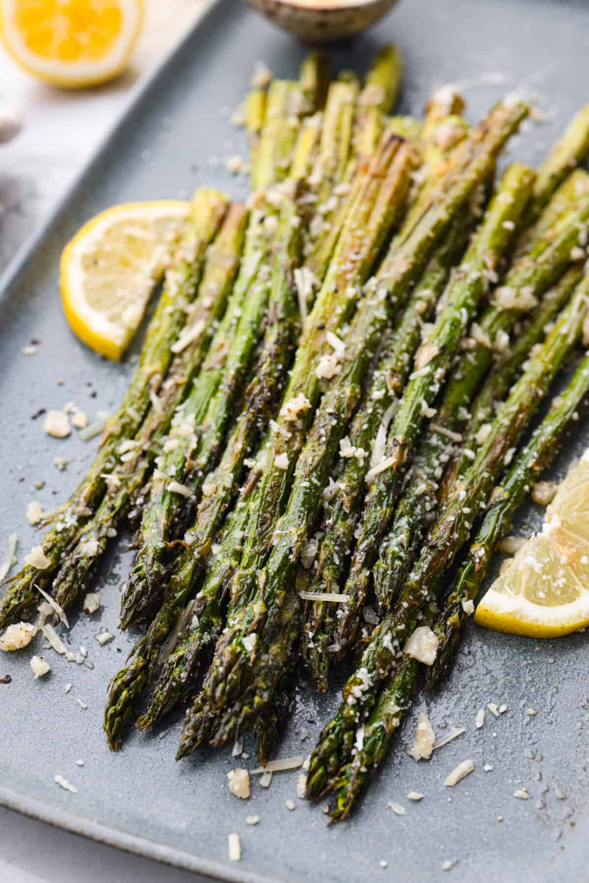 Close view of roasted lemon parmesan garlic asparagus on a platter.