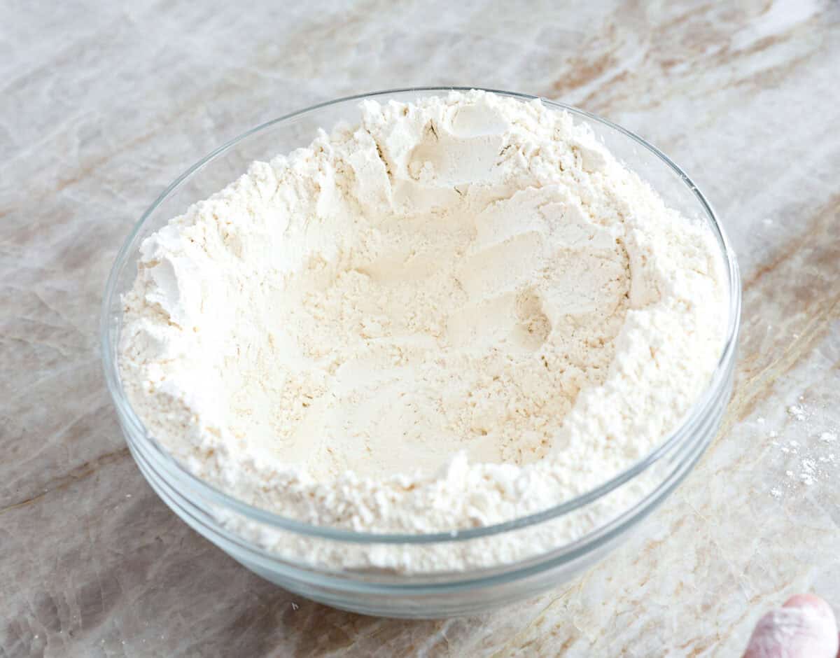 Second photo of the flour, salt, and yeast in a bowl shaped into a well.