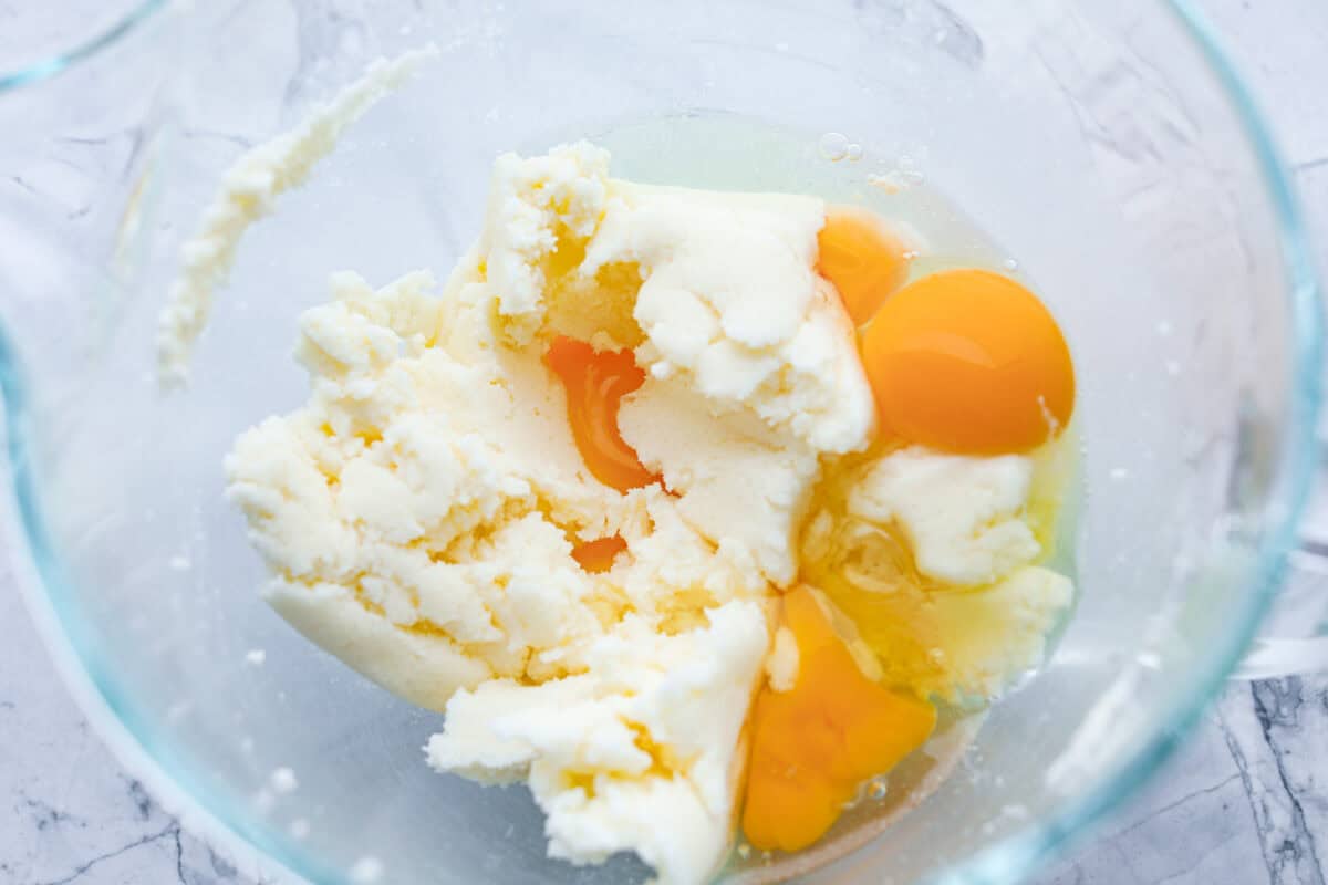 Eggs being beaten in a glass bowl with the surge and butter mixture. 