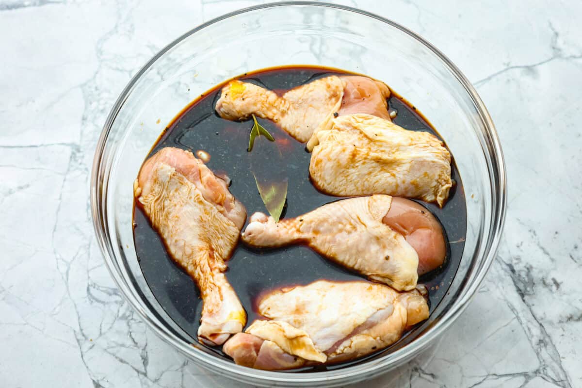 Overhead shot of raw chicken in marinade in large bowl. 