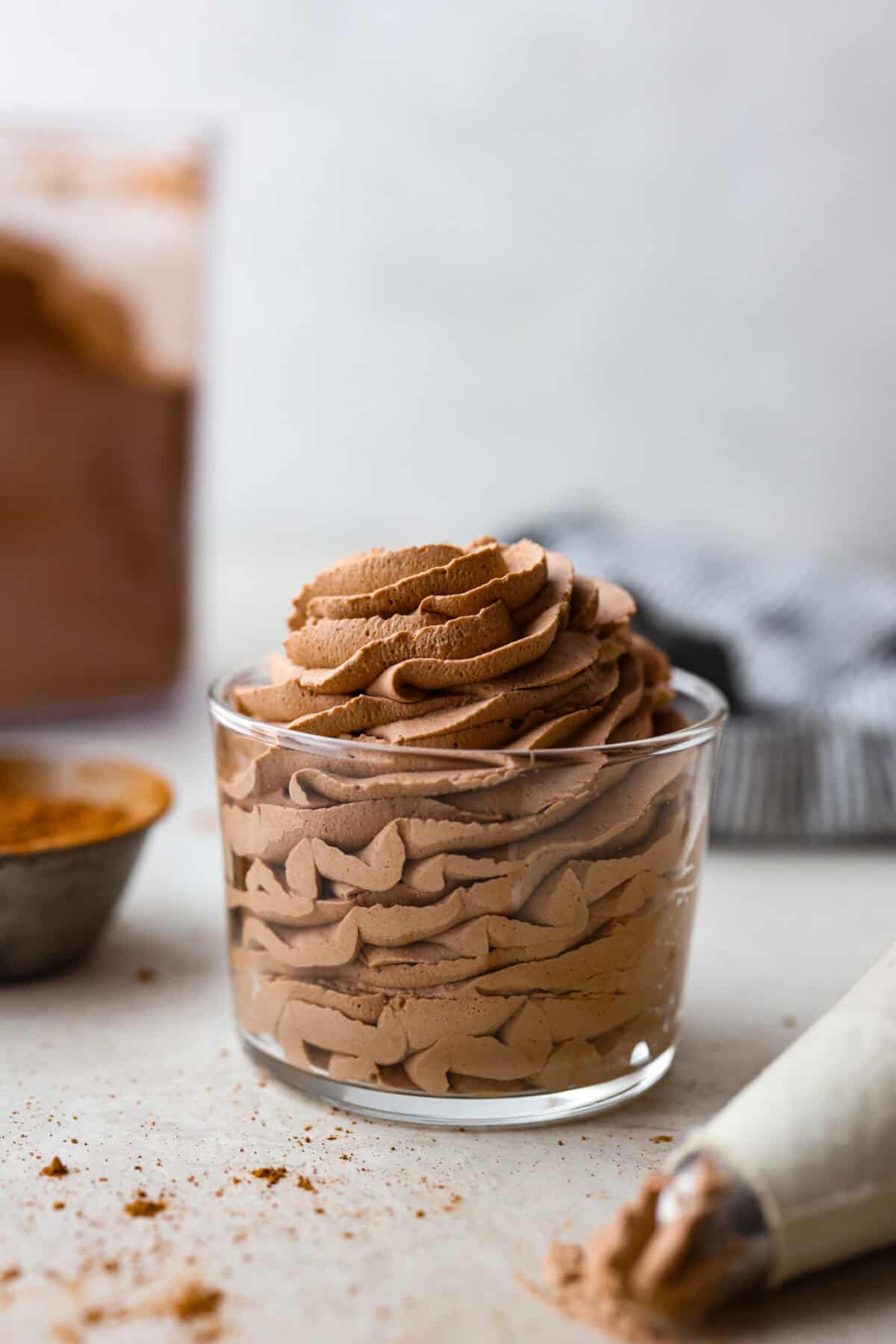 Side view of a glass with piped chocolate whipped cream inside. 