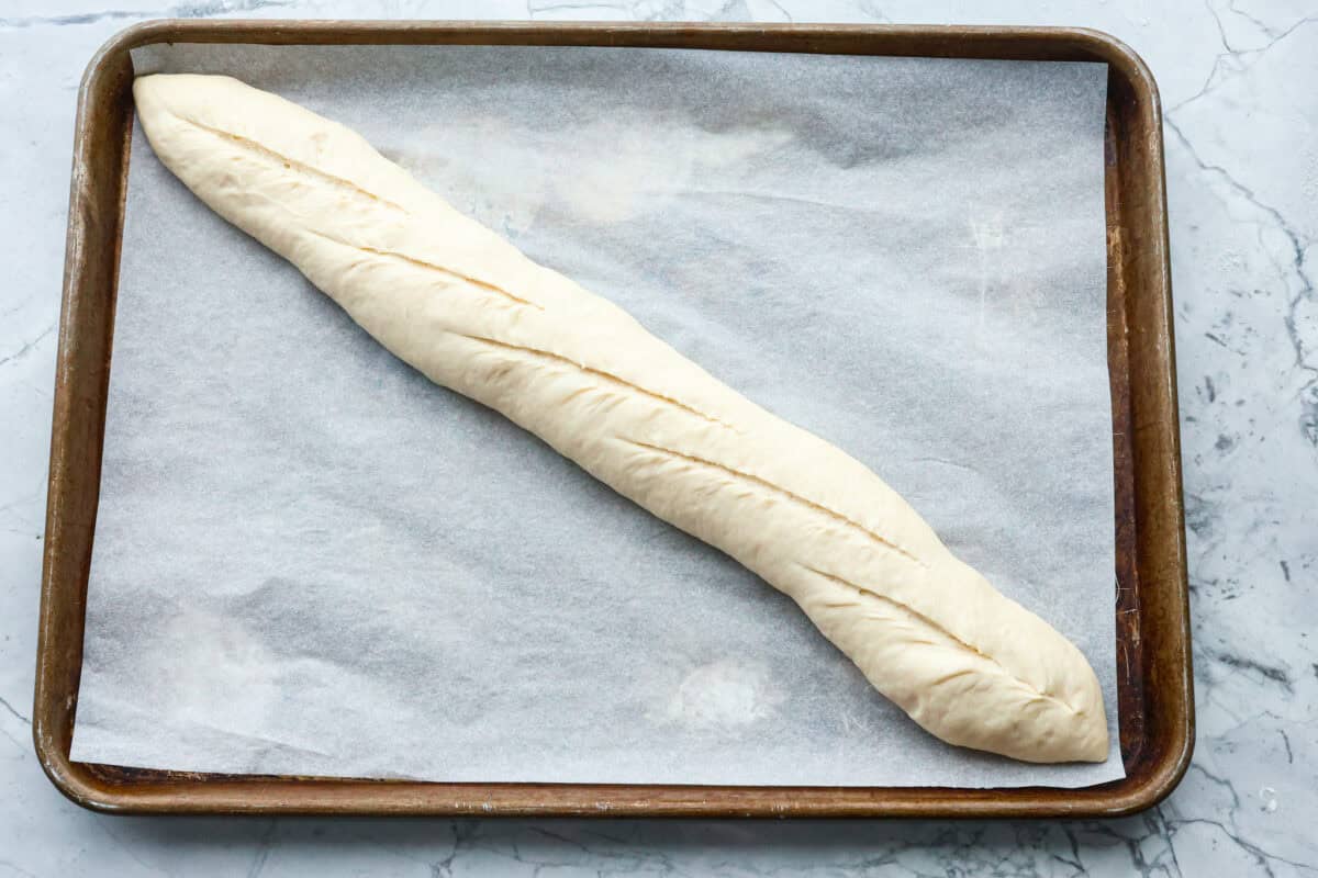 Overhead shot of dough loaf with score marks across the top. 