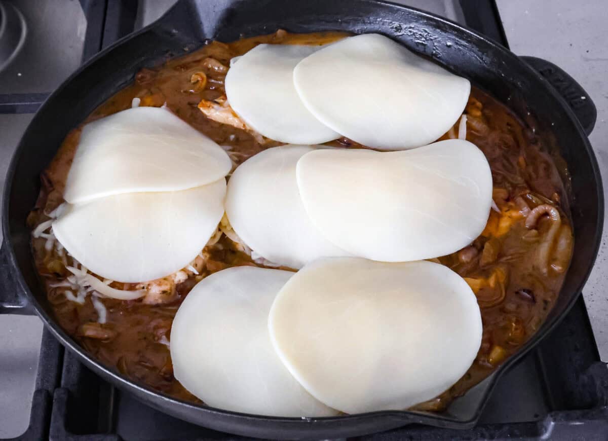 Overhead shot of cheese on top of chicken breasts in skillet completing the French onion chicken. 