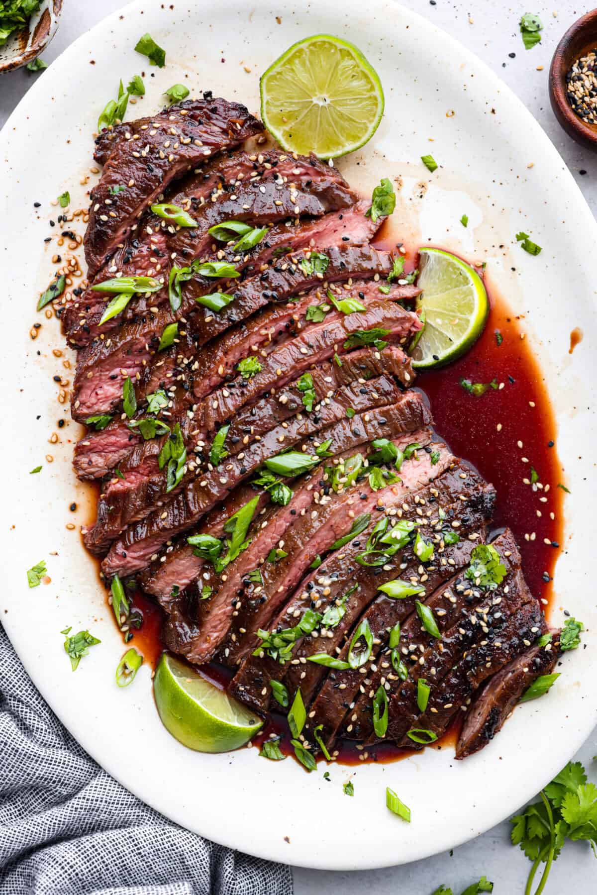 Overhead shot of flank steak sliced up limes on the side 