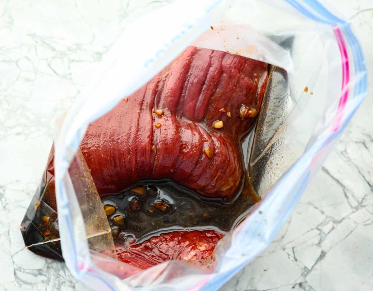 Overhead shot of flank steak in larg zip-lock bag with marinade. 