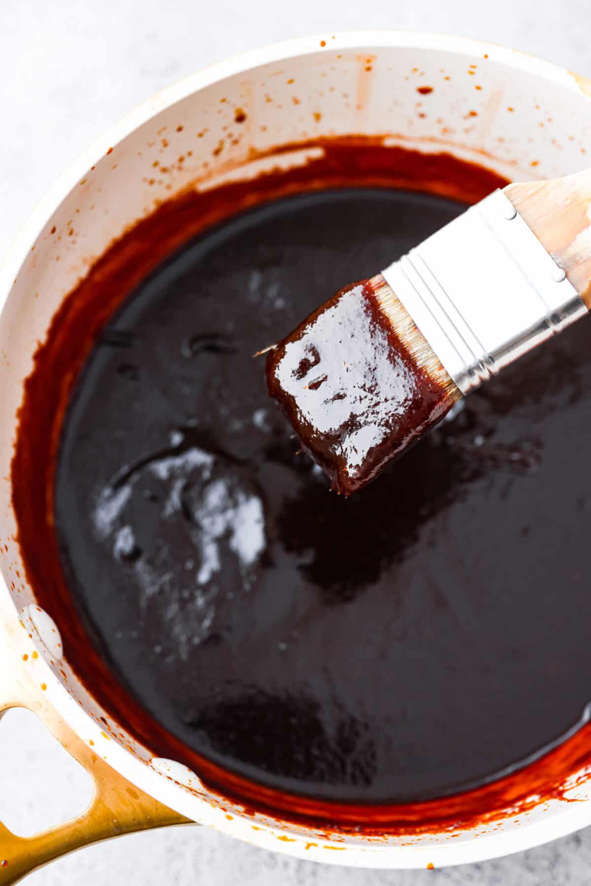 Top view of bbq sauce in a saucepan with a basting brush.