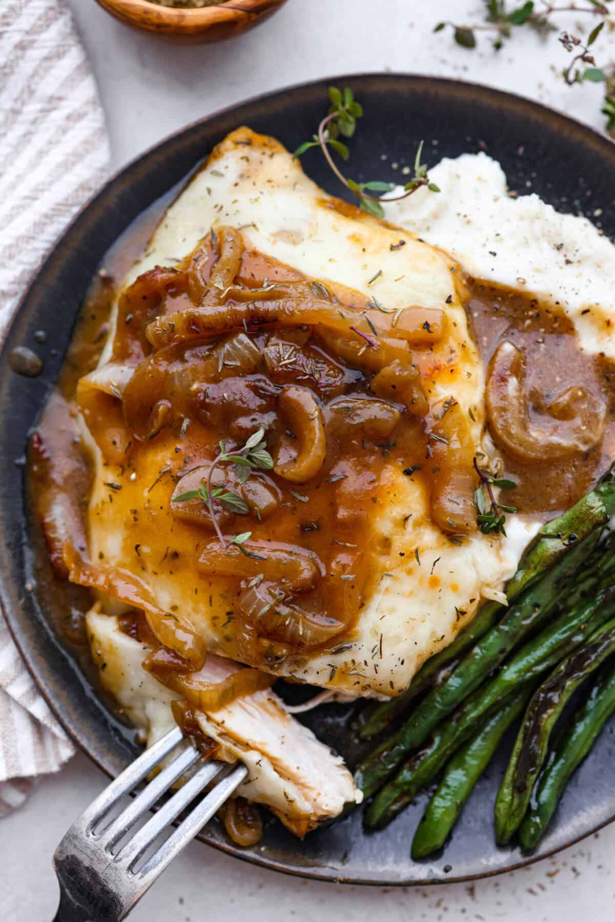 Overhead shot of plated chicken on potatoes with a bite on a fork. 