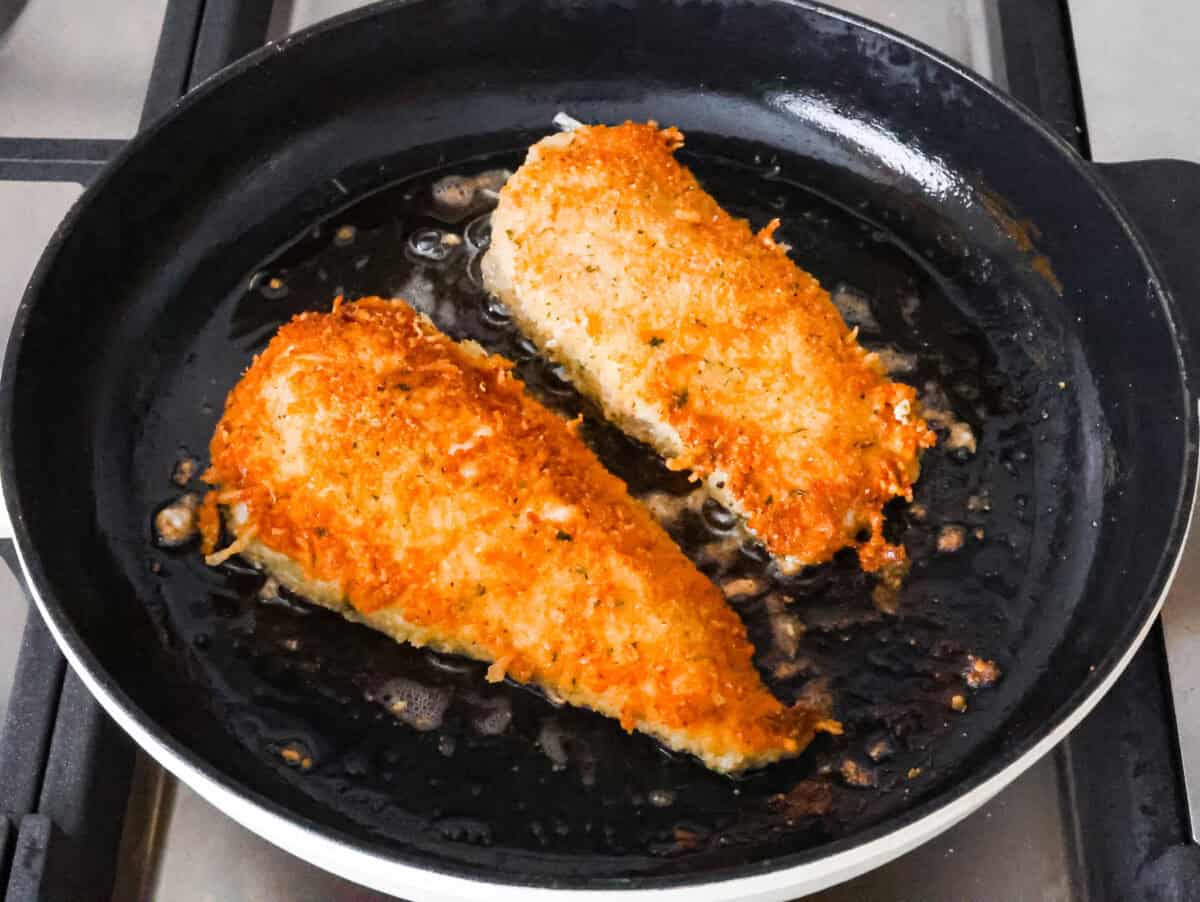 Overhead shot of breaded chicken being fried on a skillet. 