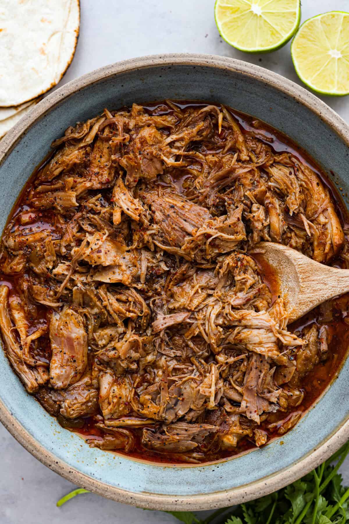 Sweet pork in large serving bowl with wooden spoon. 