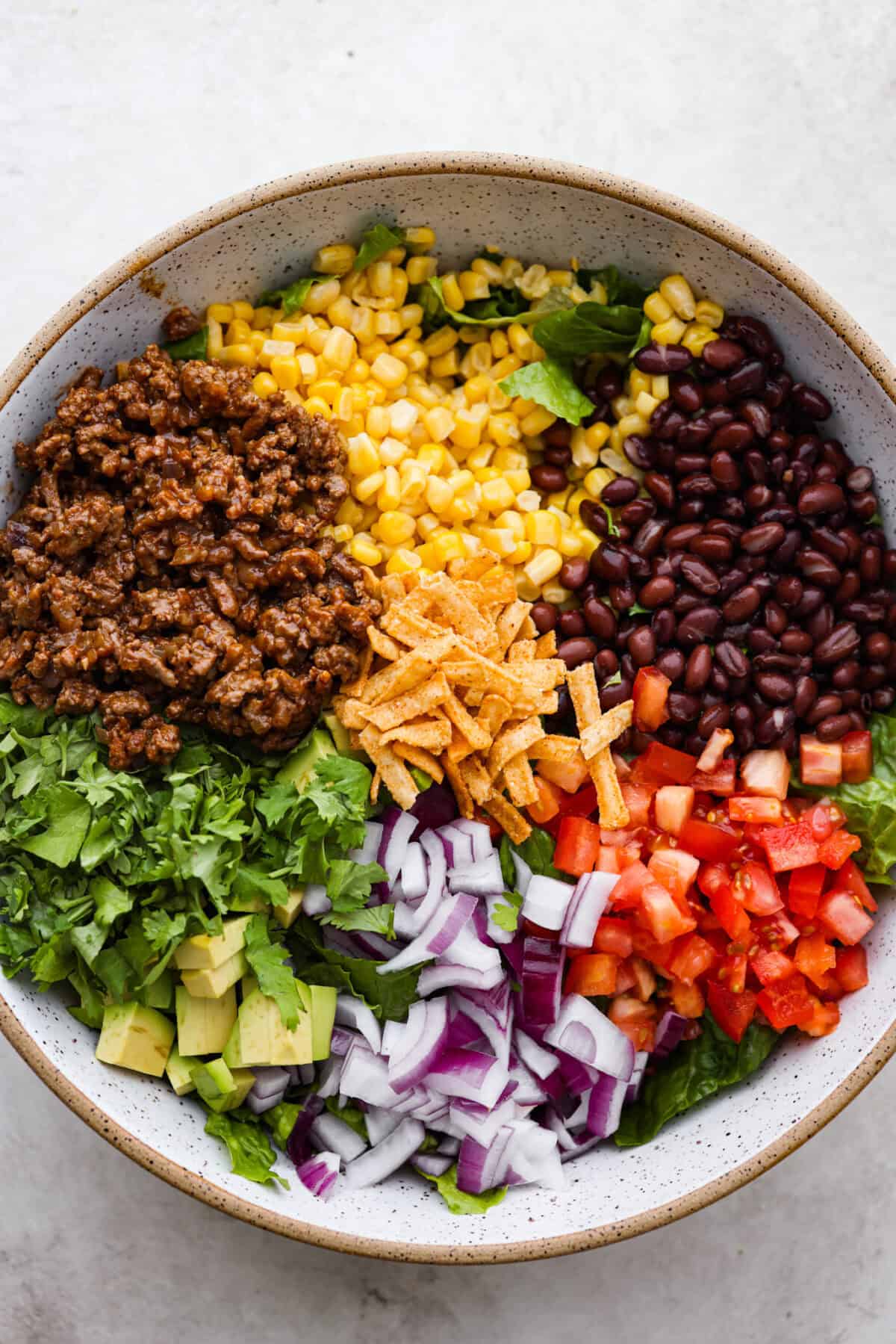 Overhead shot of separated salad ingredients in large bowl. 