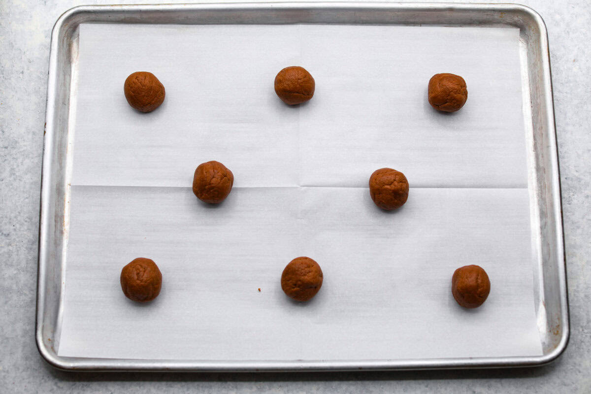 Cookie dough balls on a baking sheet with parchment paper. 