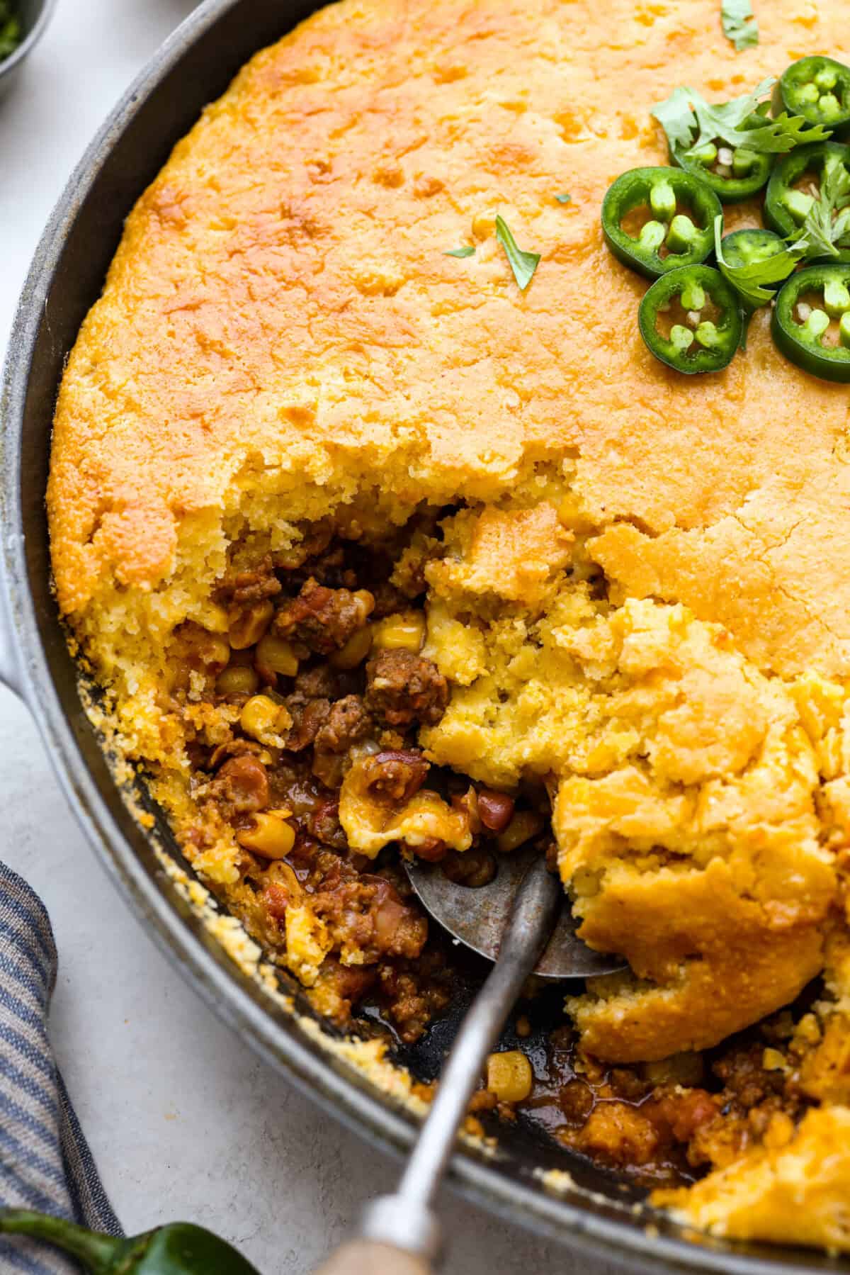 Close up shot of cowboy cornbread casserole dish with spoon inside. 