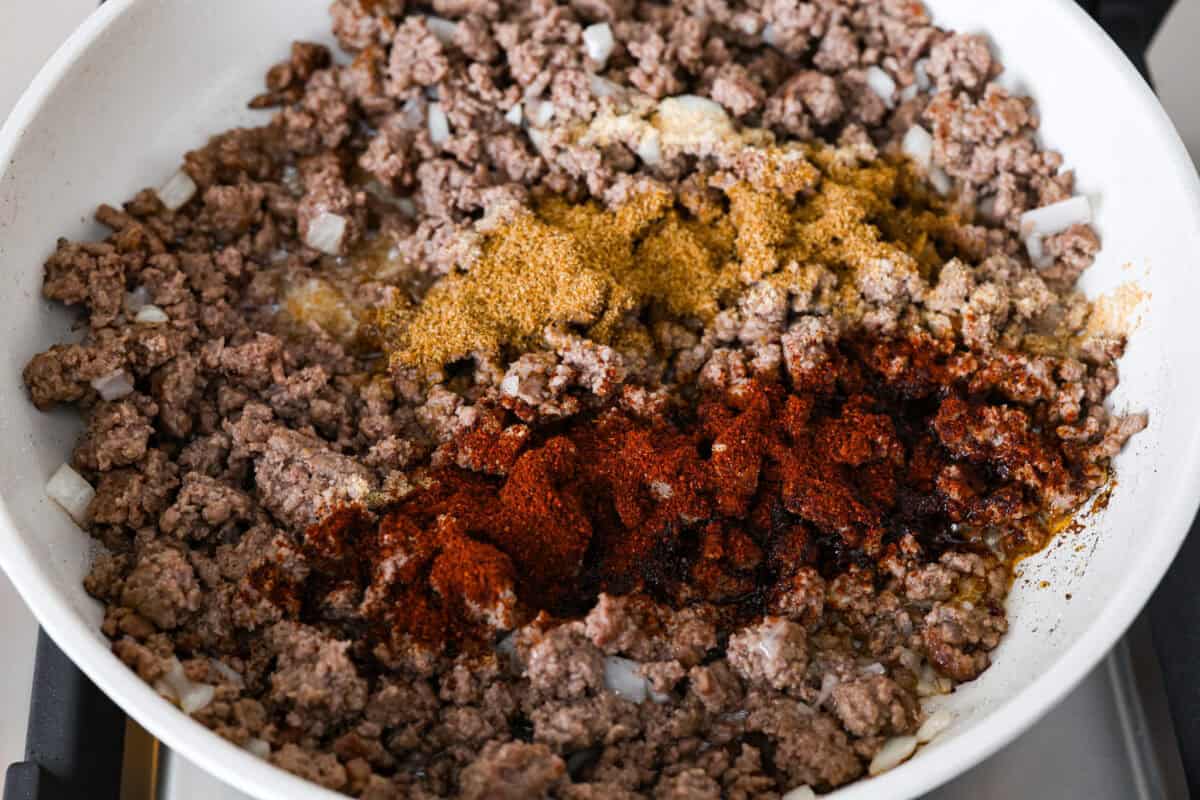 Angle shot of ground beef mixture with seasonings on top. 