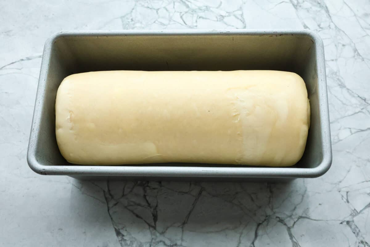 Overhead shot of rolled dough in loaf pan. 