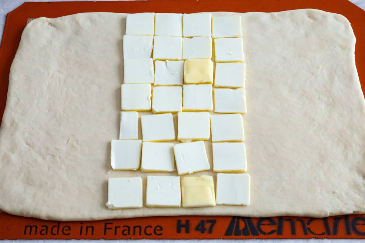 Overhead shot of 9x14 rectangular dough with butter squares placed down the middle third of the rectangle. 