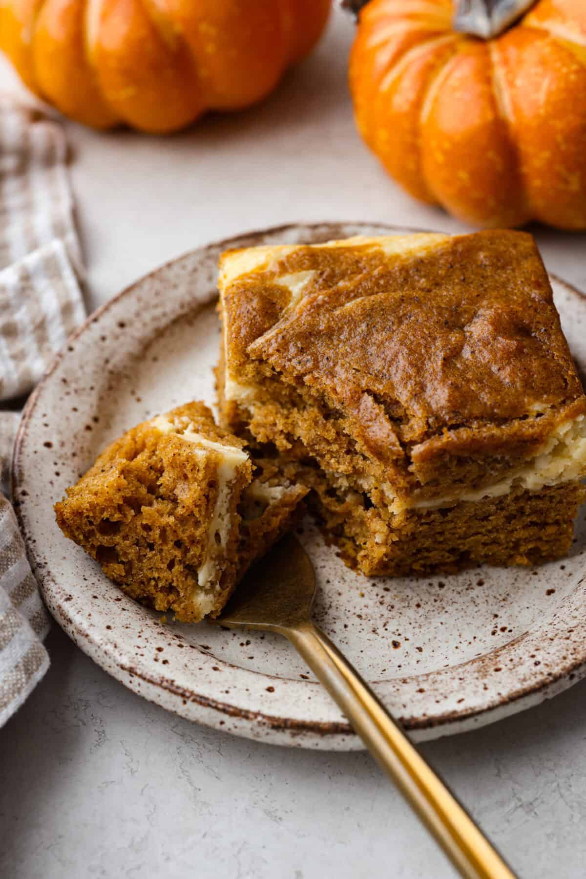 Angle shot of a plate pumpkin roll bar with a bite on a gold spoon. 