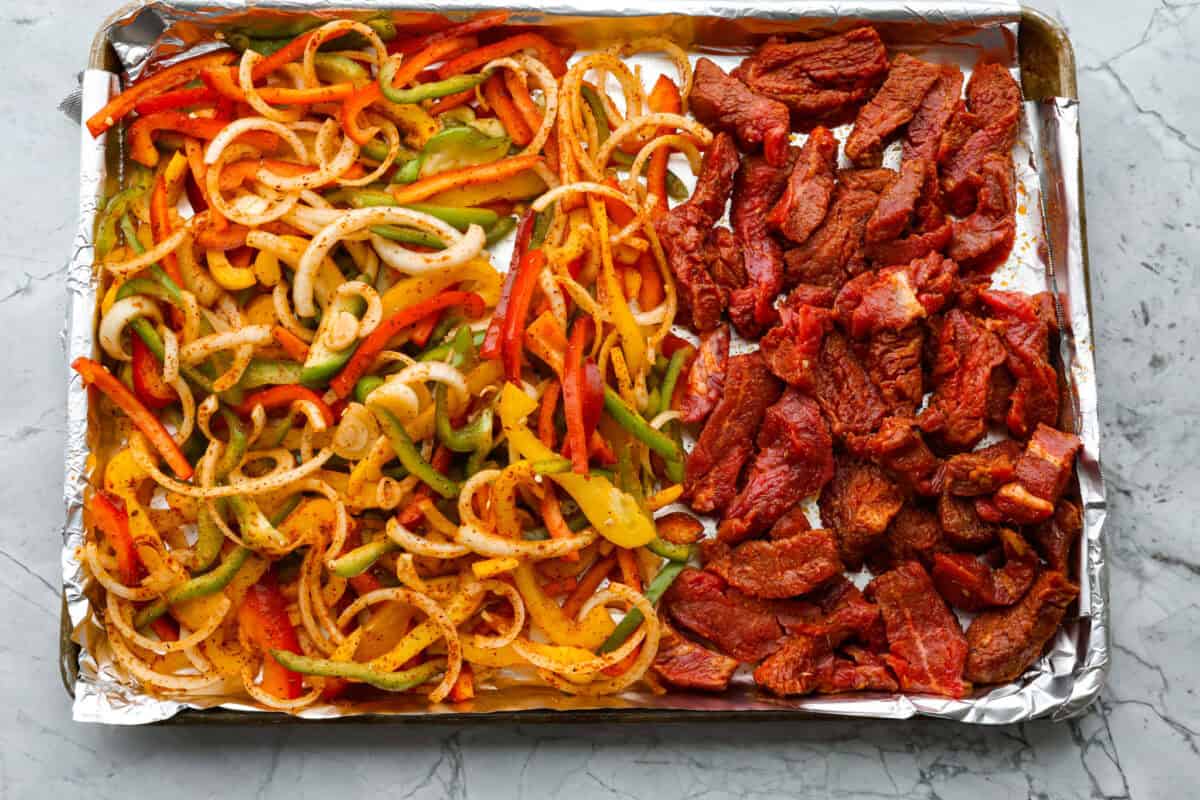 Overhead shot of veggies and steak spread out on a pan. 