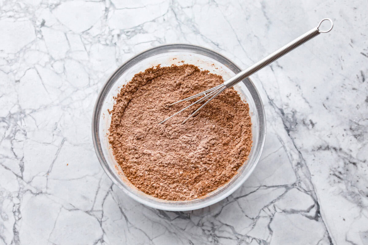 Overhead shot of dry ingredients in a glass bowl with a whisk. 