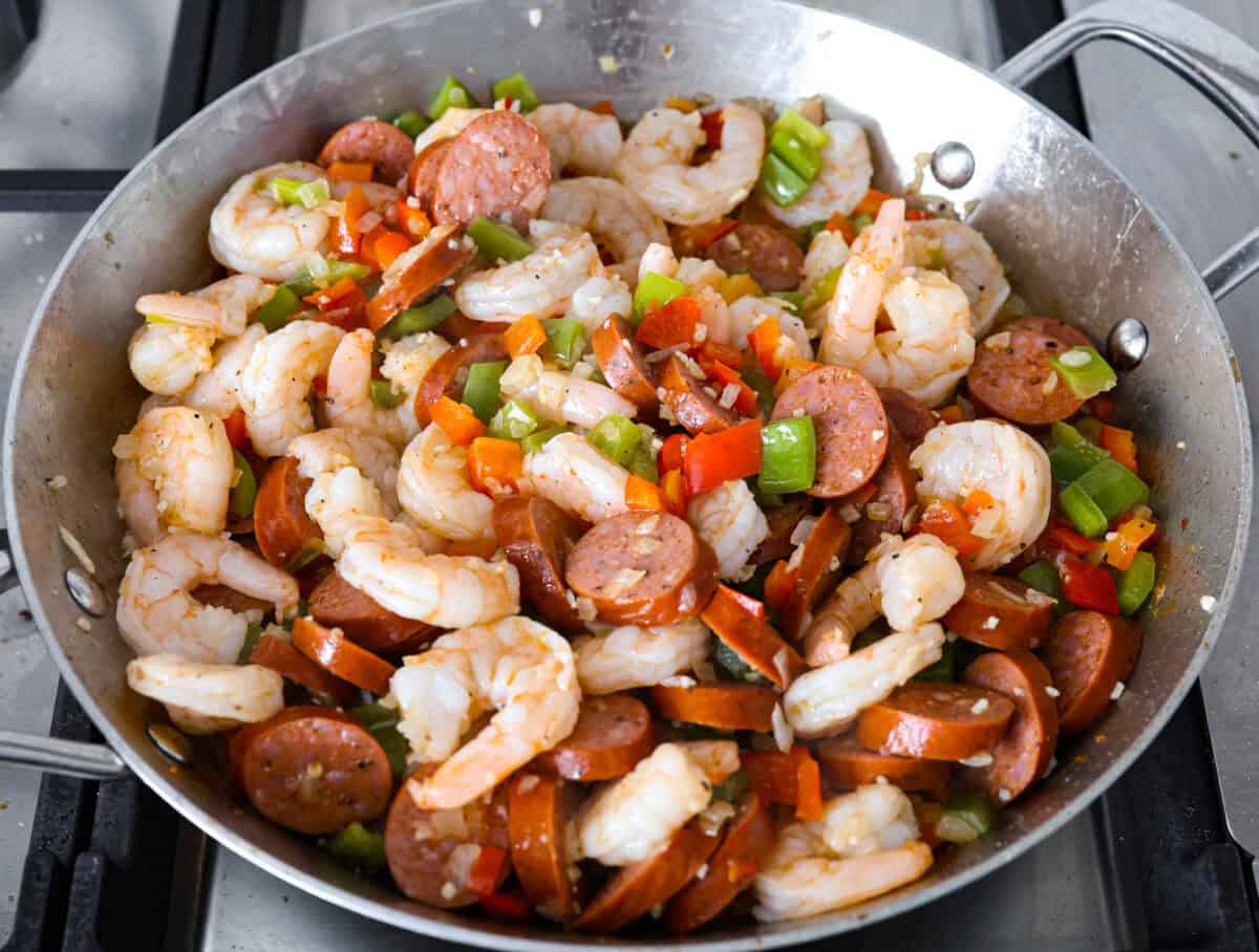 Overhead shot of the shrimp, sausage and vegetables cooking in the skillet. 