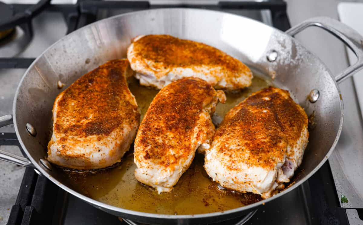 Angle shot of the chicken being seared in a pan. 