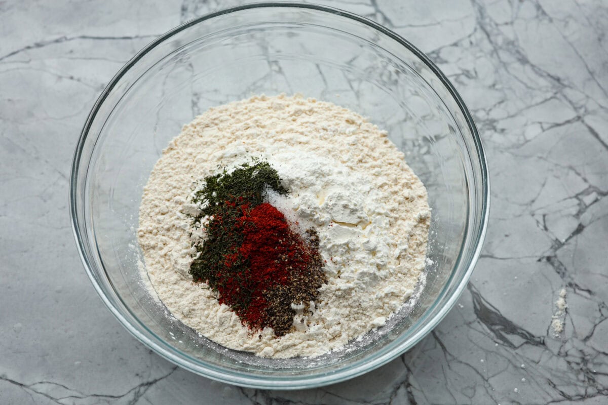 Overhead shot of flour, paprika, dried dill salt and pepper in a glass bowl.