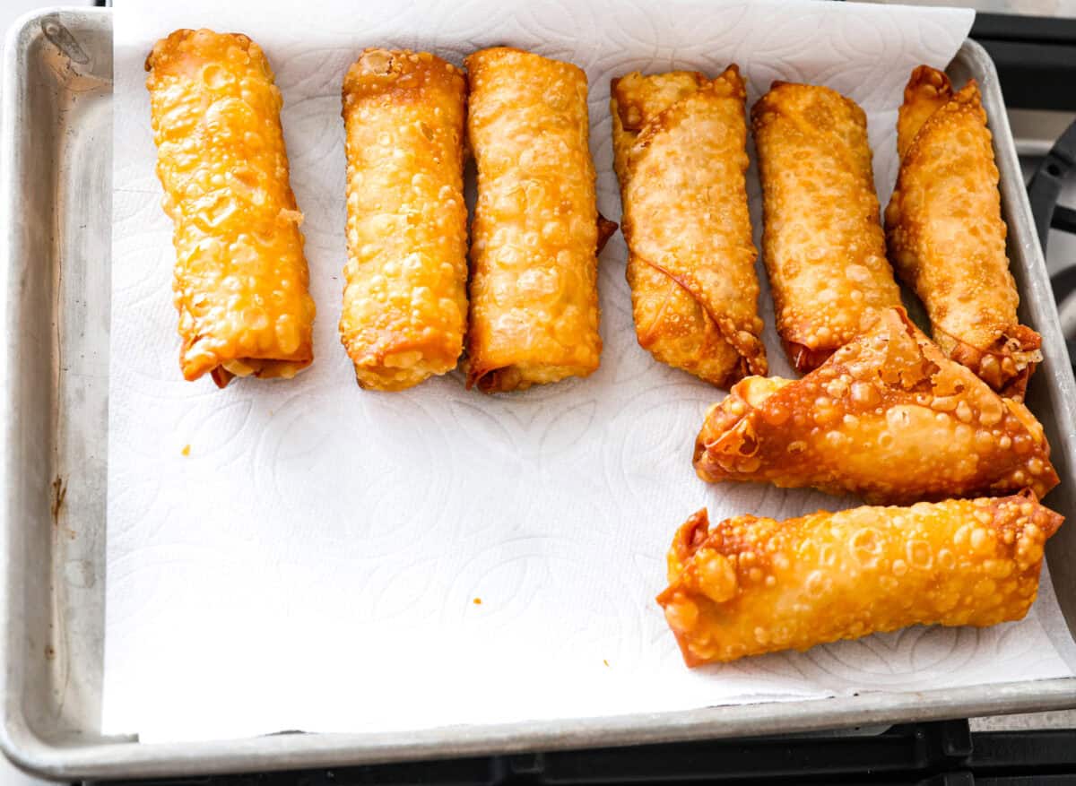 Overhead shot of fried shrimp egg rolls cooling on a baking sheet with parchment paper. 