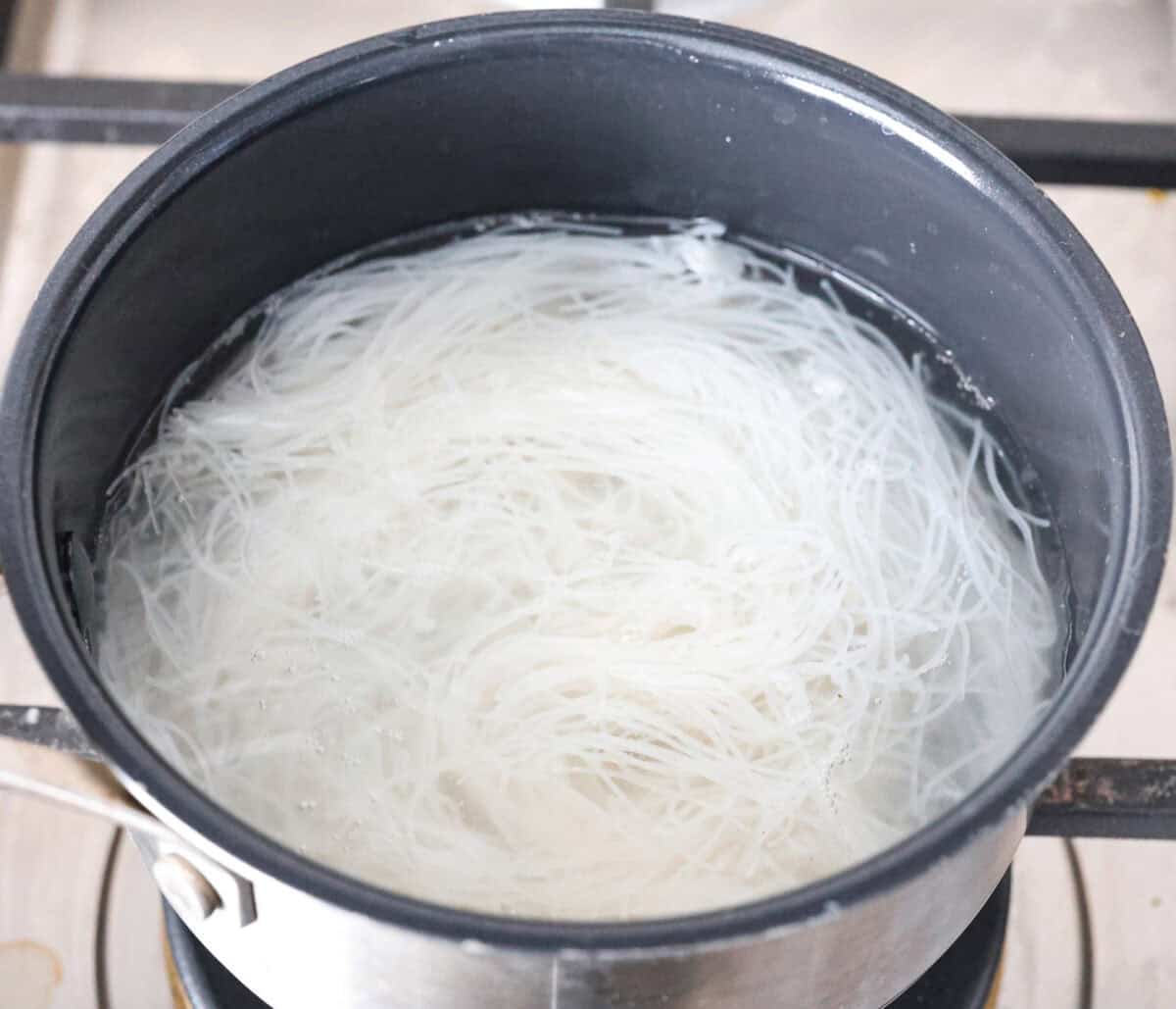 Overhead shot of vermicelli noodles being cooked in a pot. 