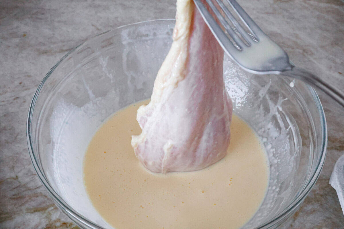 Overhead shot of chicken cutlet in cream and egg mixture. 