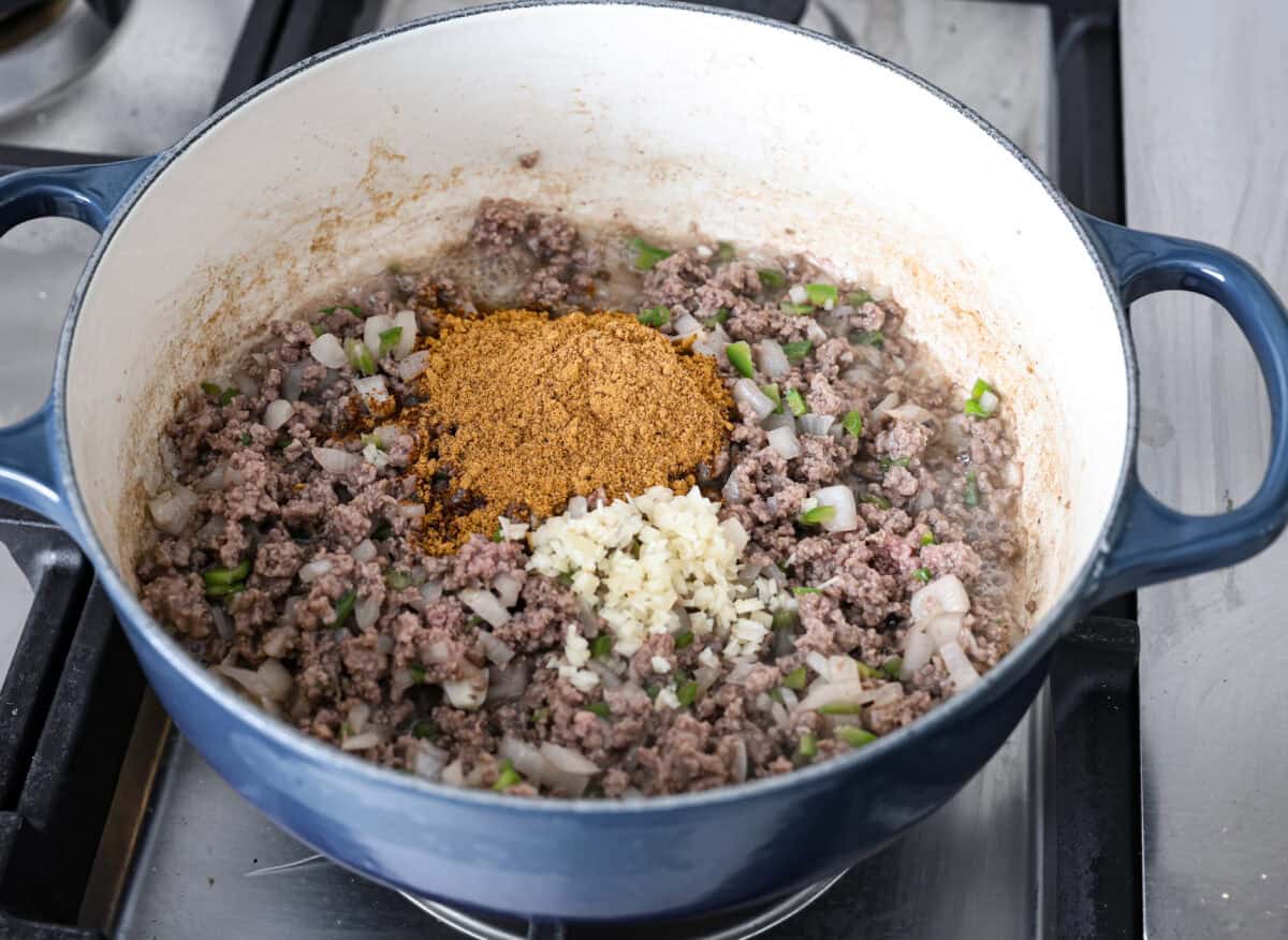 Angle shot of cooked beef mixture with minced garlic and taco seasoning added to it. 