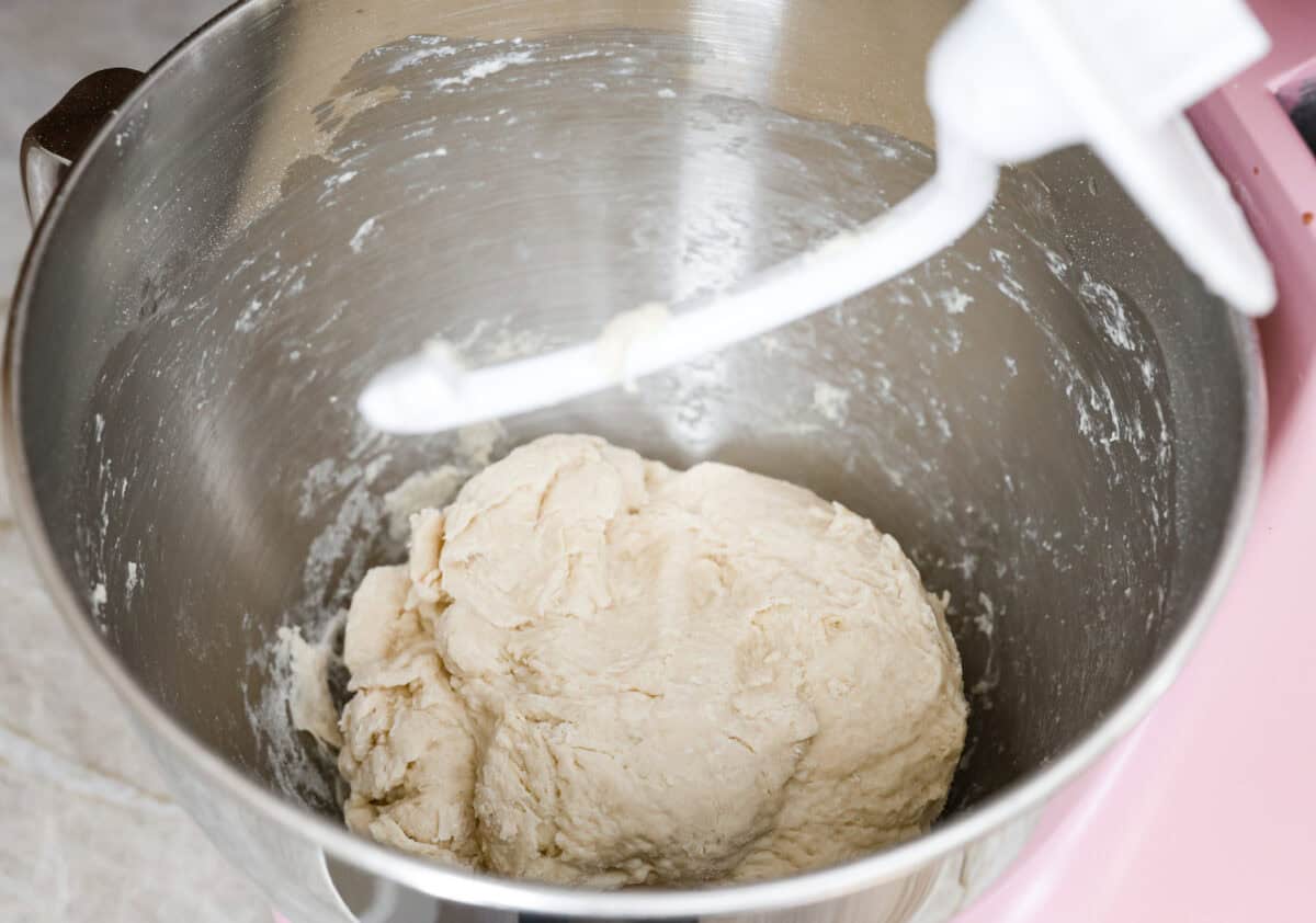 Angle shot of dough ball being formed in the bottom of a stand mixer. 