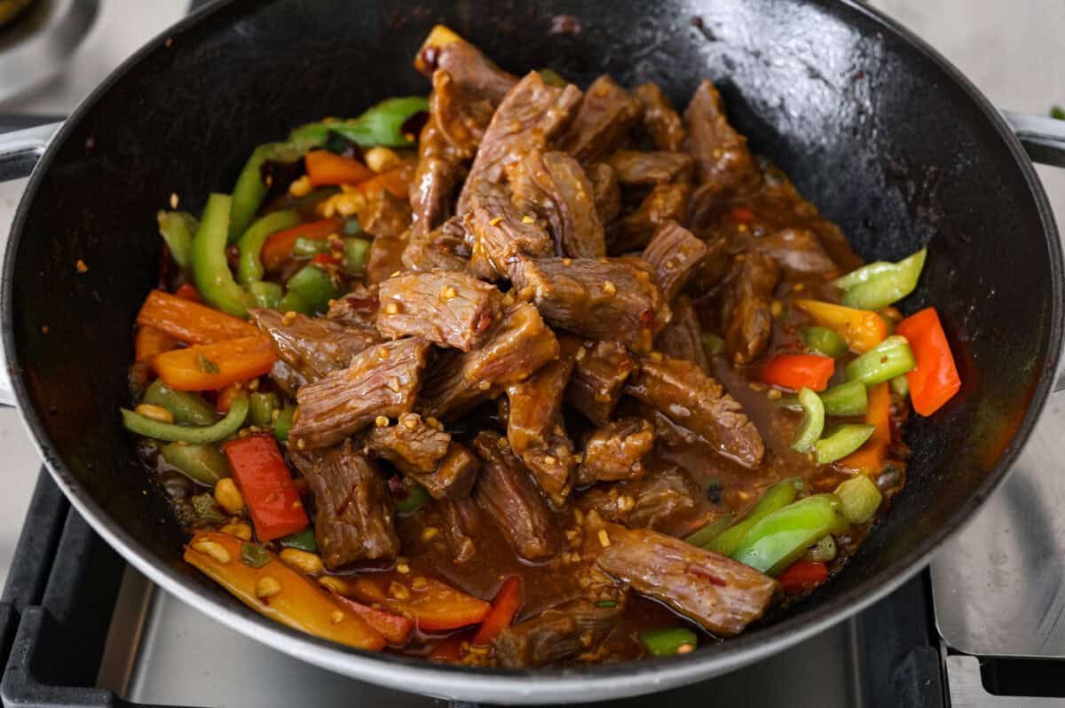 Close up shot of cooked kung pao  beef being added back to the wok with the veggies. 