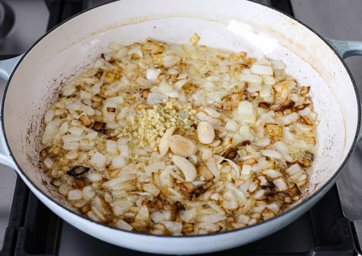 Angle shot of onions garlic and ginger being sautéed in the ghee and oil. 