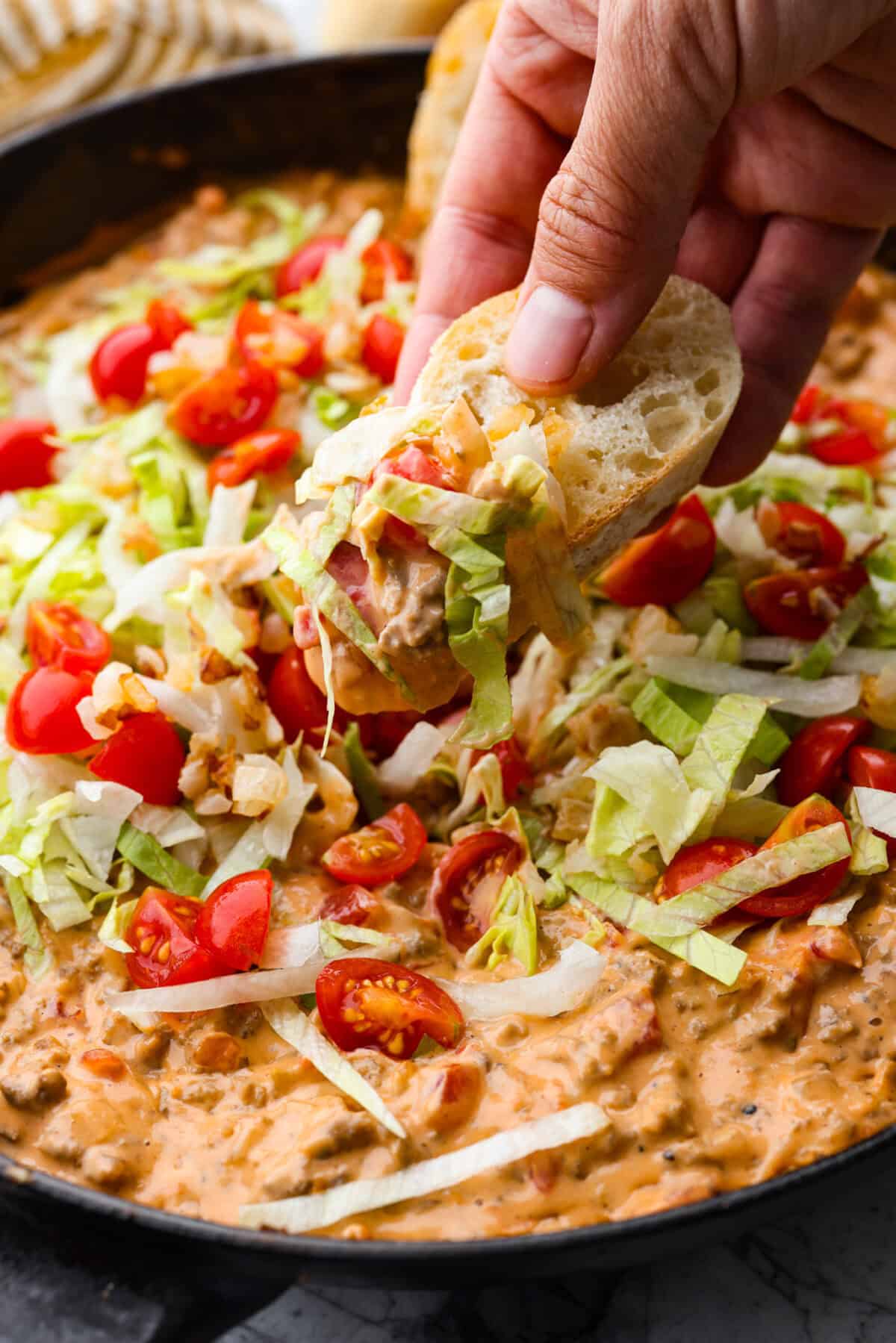 Close up shot of someone getting a bite of dip on a crust of bread. 