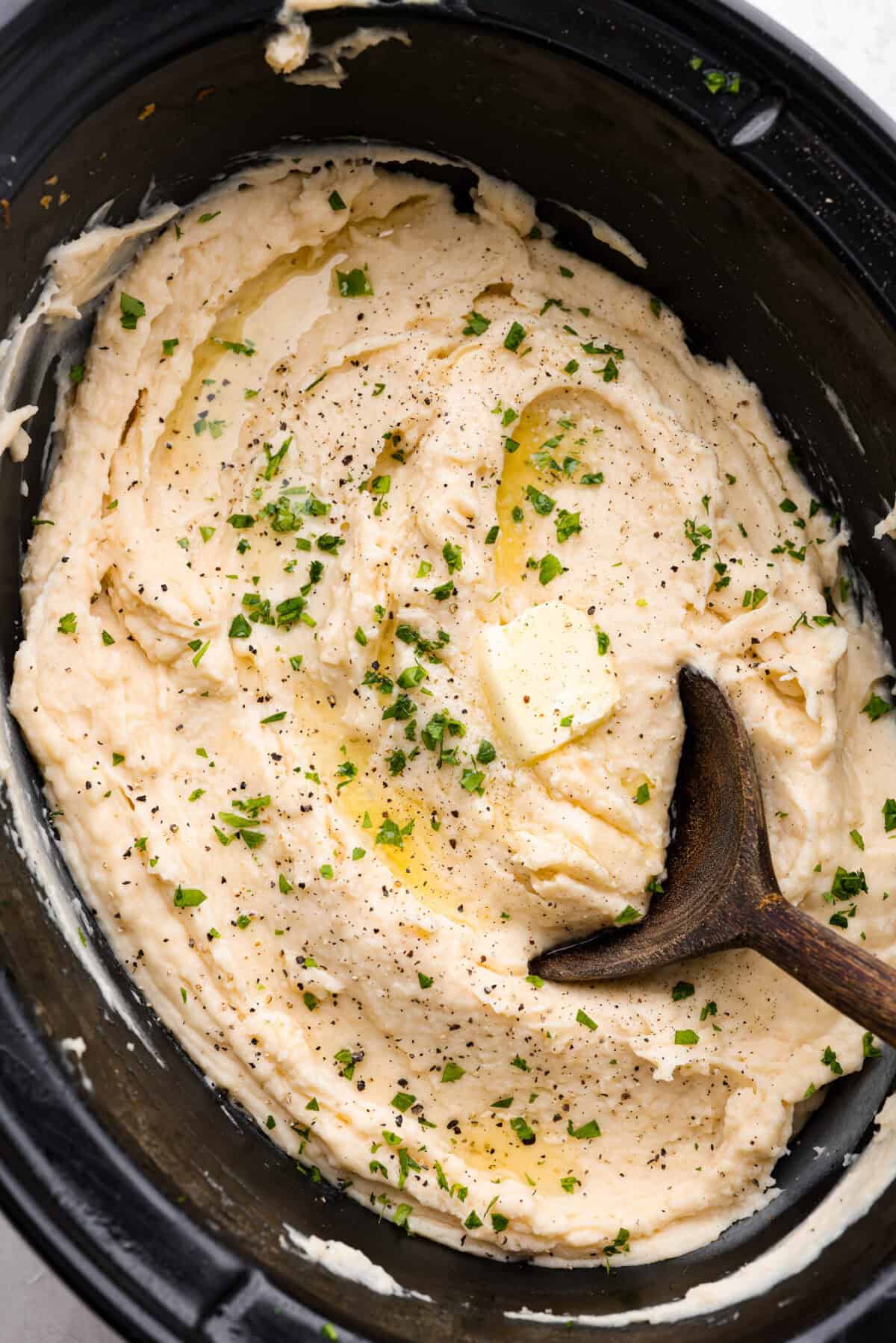 Overhead shot of million dollar mashed potatoes with wooden serving spoon.