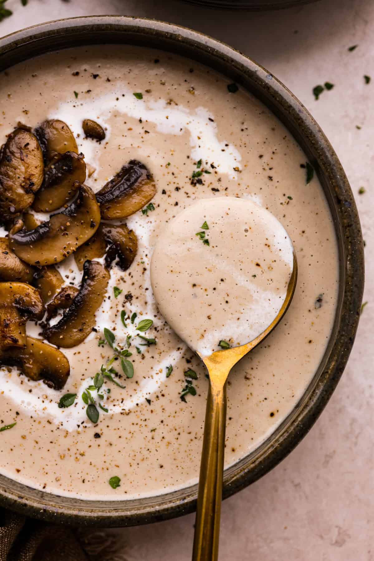 Overhead shot of a bowl of mushroom bisque with a spoon scooping out a bite. 