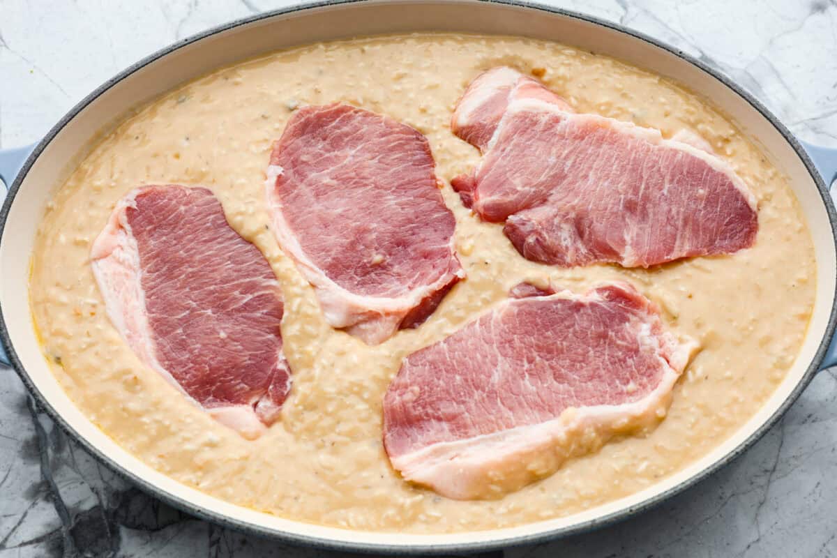 Overhead shot of rice and soup mixture in the bottom of a baking dish with pork chops on top. 