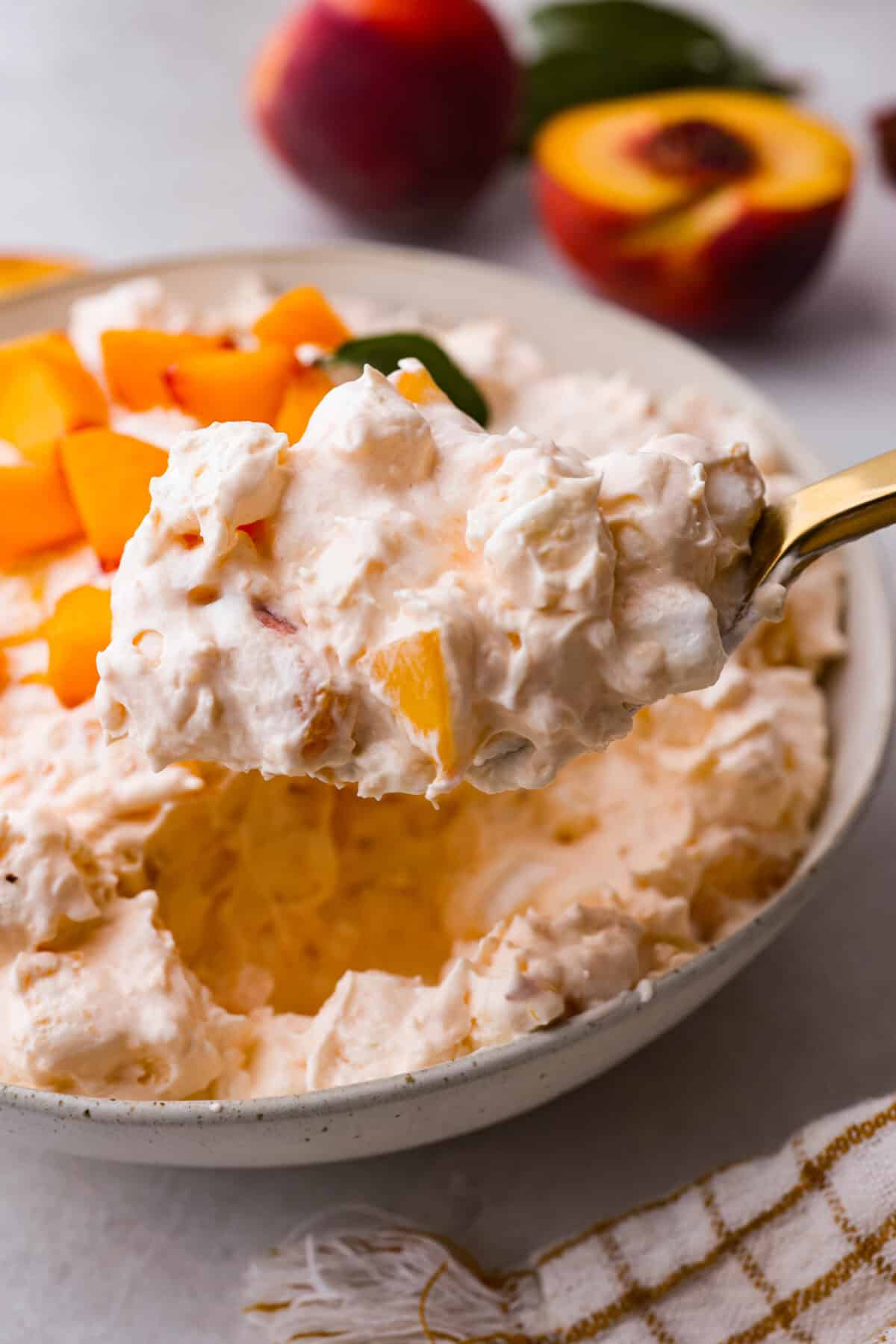 A close up of a spoonful of fresh peach fluff salad.