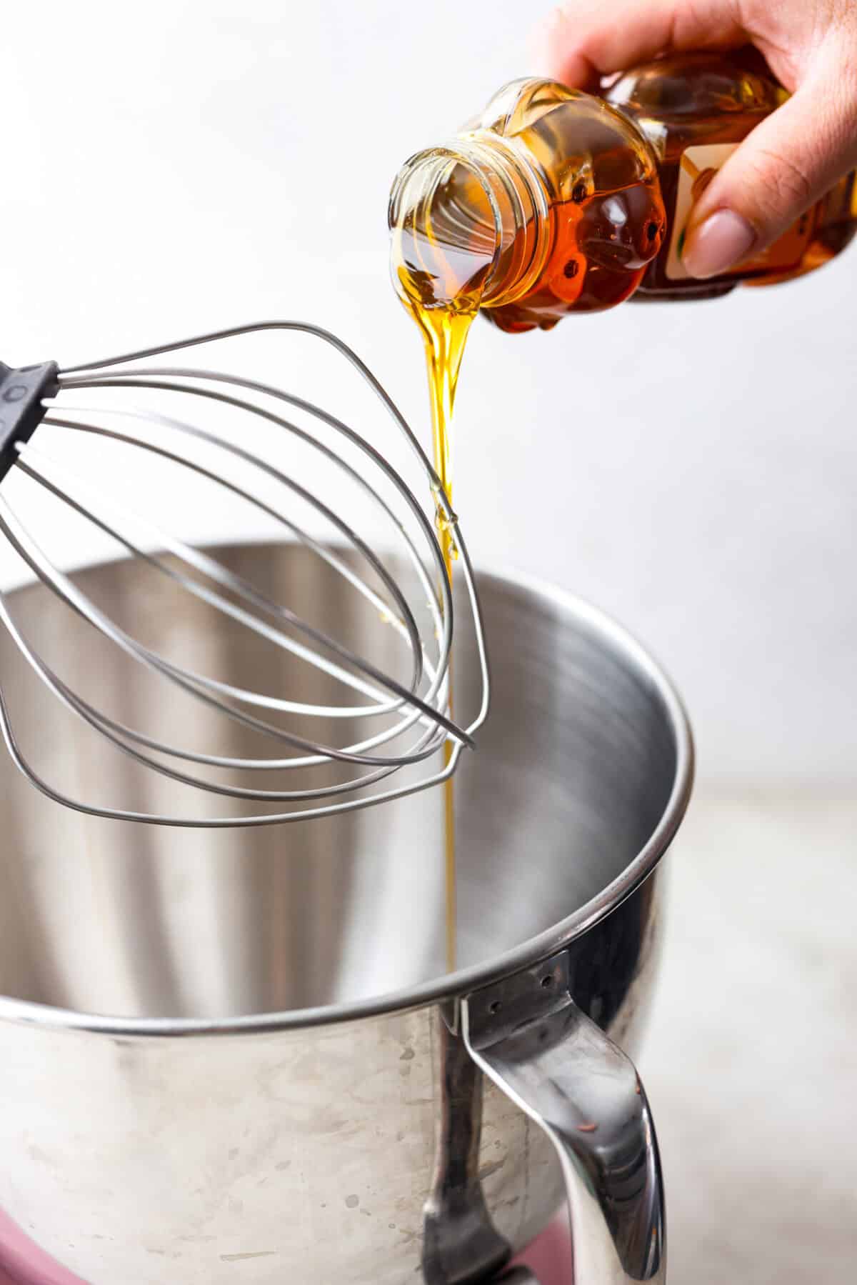 Side shot of someone pouring honey into a stand mixer. 