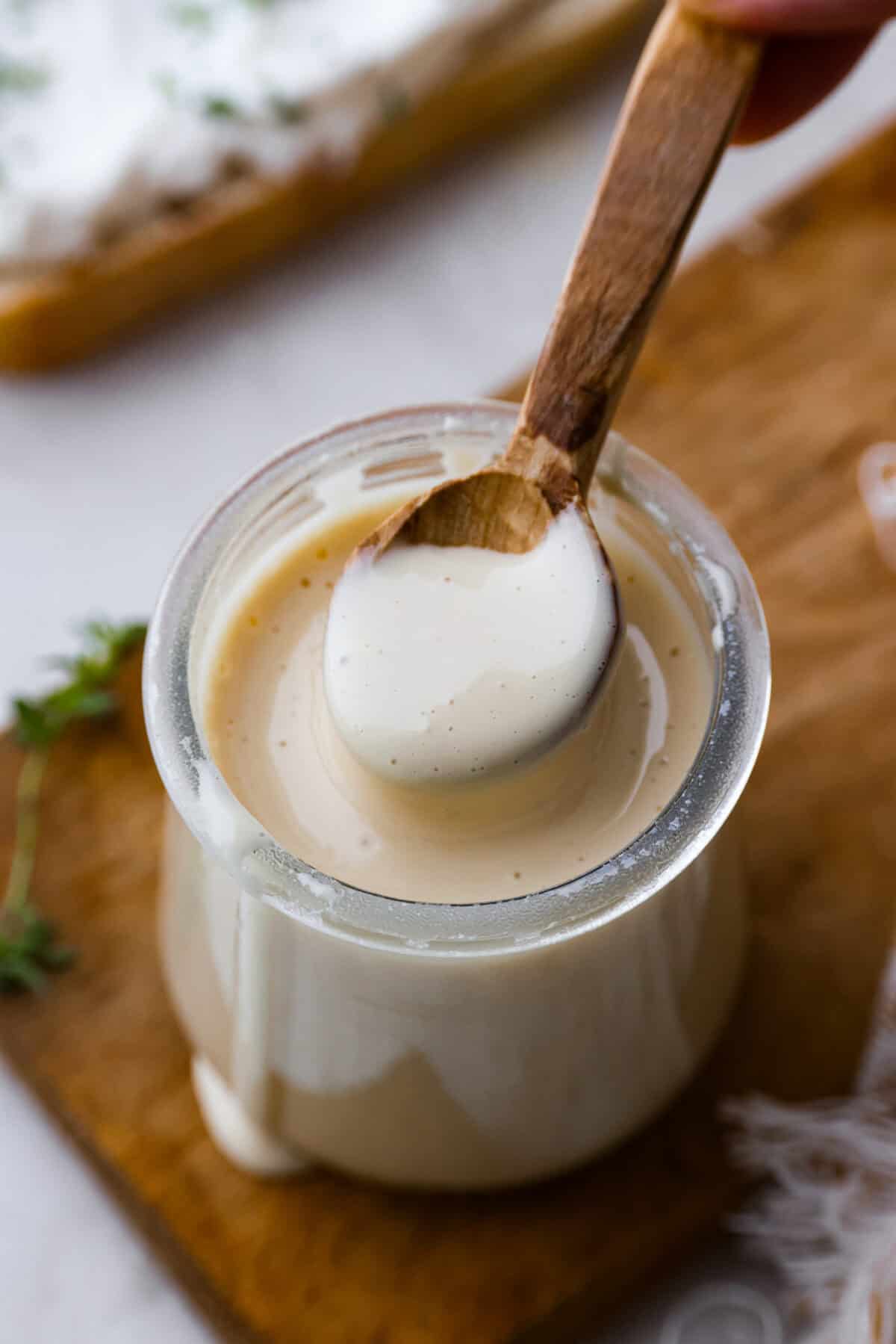 Angle shot of whipped honey in a jar with a small wooden spoon scooping some out. 