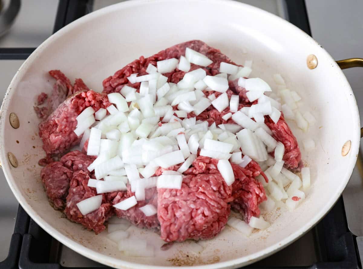 Overhead shot of ground beef and onions cooking in a skillet. 