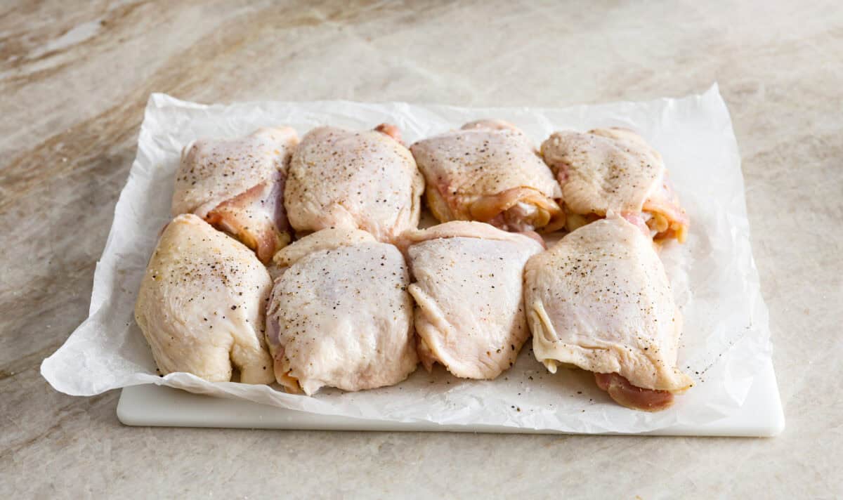 Angle shot of chicken thighs seasoned with salt and pepper. 