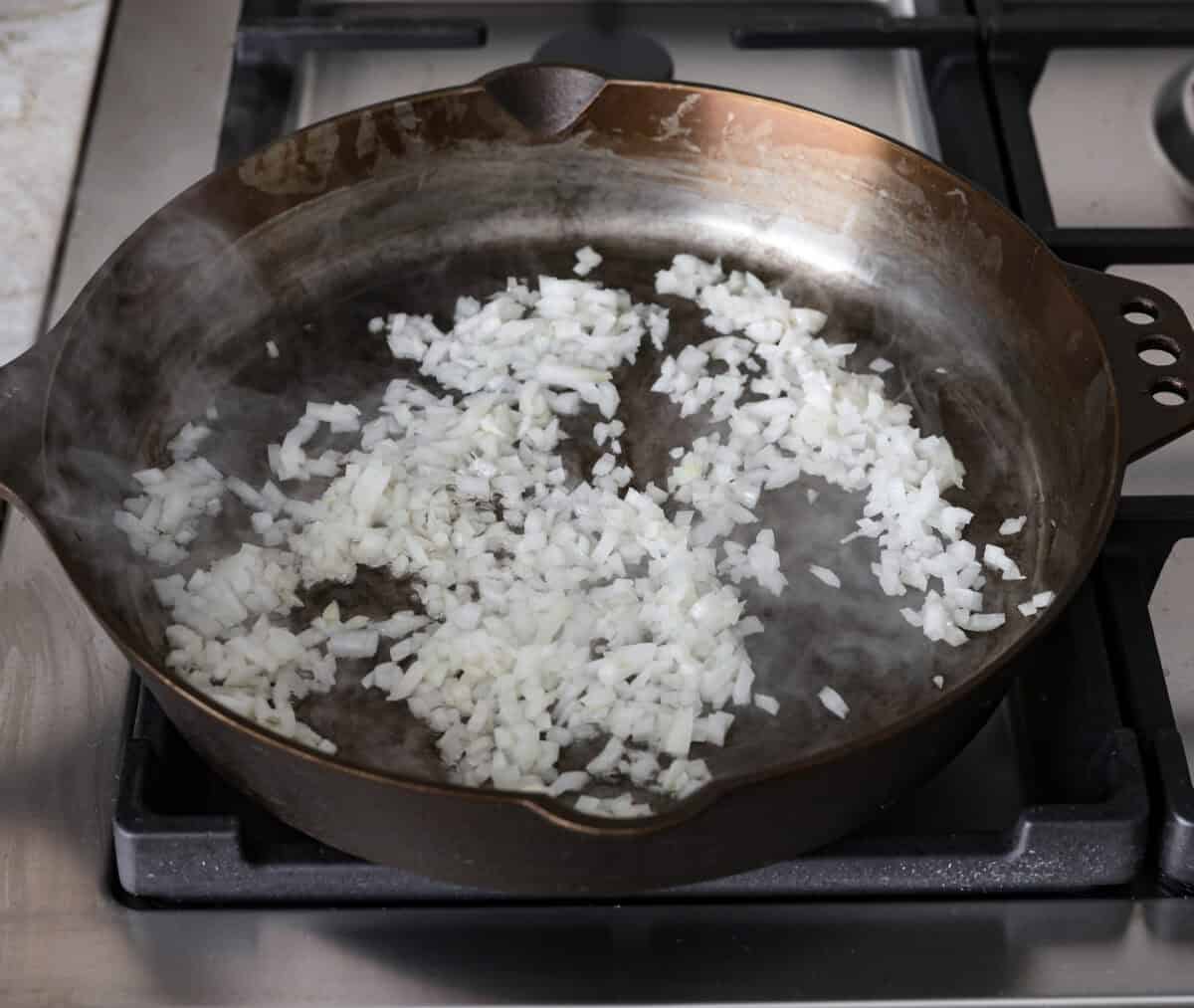 Angle shot of onions cooking in a skillet. 