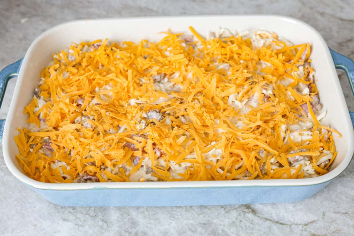 Angle shot of casserole ingredients in a baking dish covered with cheese ready to go into the oven.