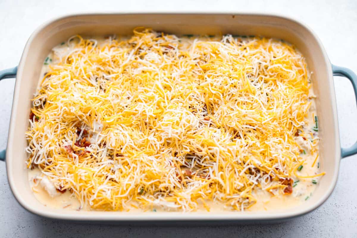 Overhead shot of egg, meat and biscuits covered with cheese ready to go in the oven.